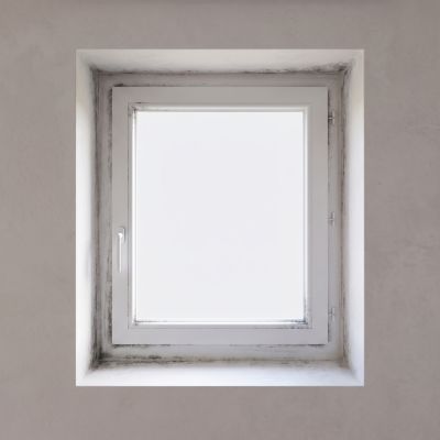 Traces noires de moisissures sur le pourtour intérieur d'un cadre de fenêtre PVC blanc